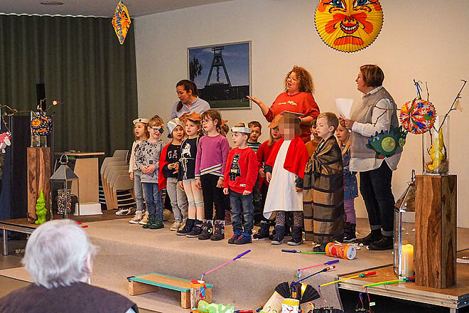 Kindergartenkinder singen auf einer kleinen Bühne mit drei Erzieherinnen.