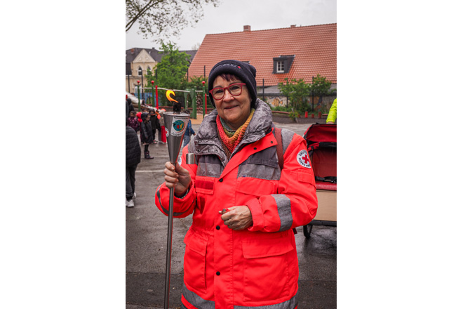 Frau mit DRK-Jacke hält eine Fackel.