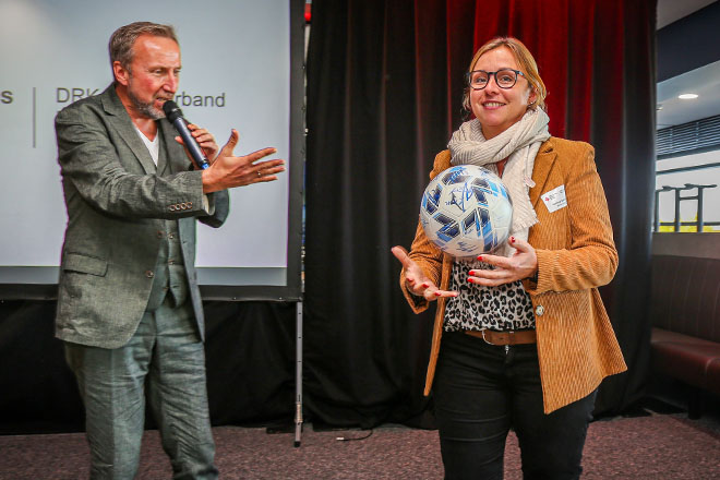 Eine Frau hält einen Fußball in der Hand.