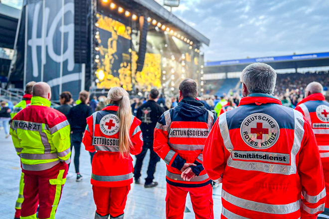 Sanitäter stehen am Rand eines Grönemeyer-Konzertes und beobachten die Menge.