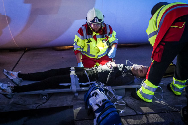 Zwei Sanitäter kümmern sich um einen auf einer Trage liegenden jungen Mann.