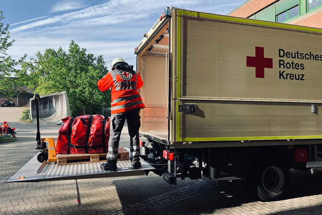 Ein DRK-Mitarbeiter auf einer Laderampe eines LKW.