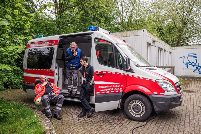 Drei Männer in DRK-Kleidung an einem DRK-Einsatzleitwagen.