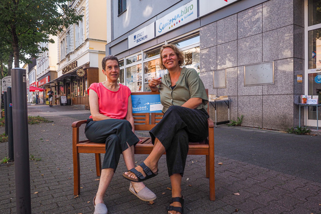 Zwei Frauen sitzen auf einer Bank.