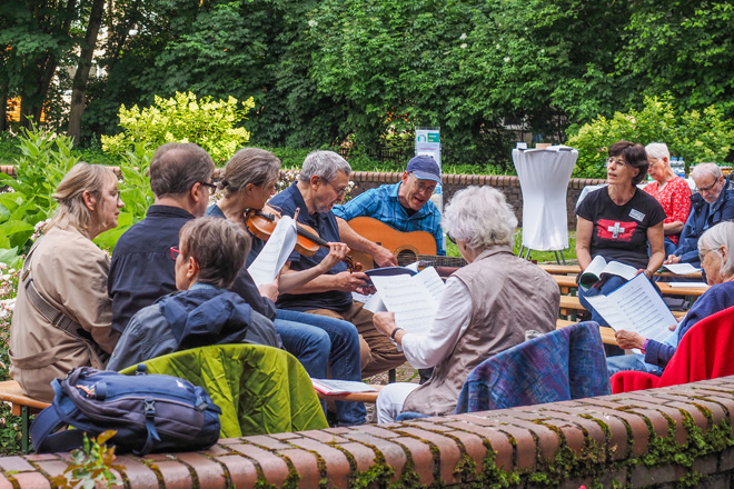 Zwei Musiker mit Geige und Gitarre werden von Sängern umrahmt.